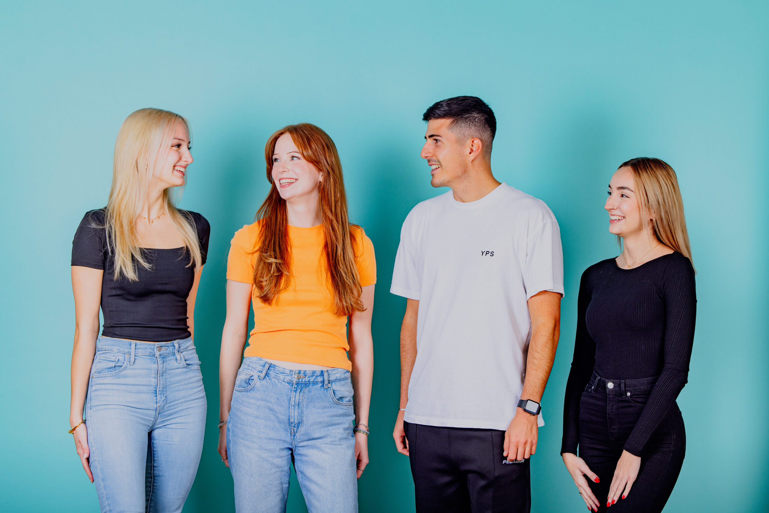 Vier glückliche junge Menschen mit strahlendem Lächeln nach der Zahnregulierung